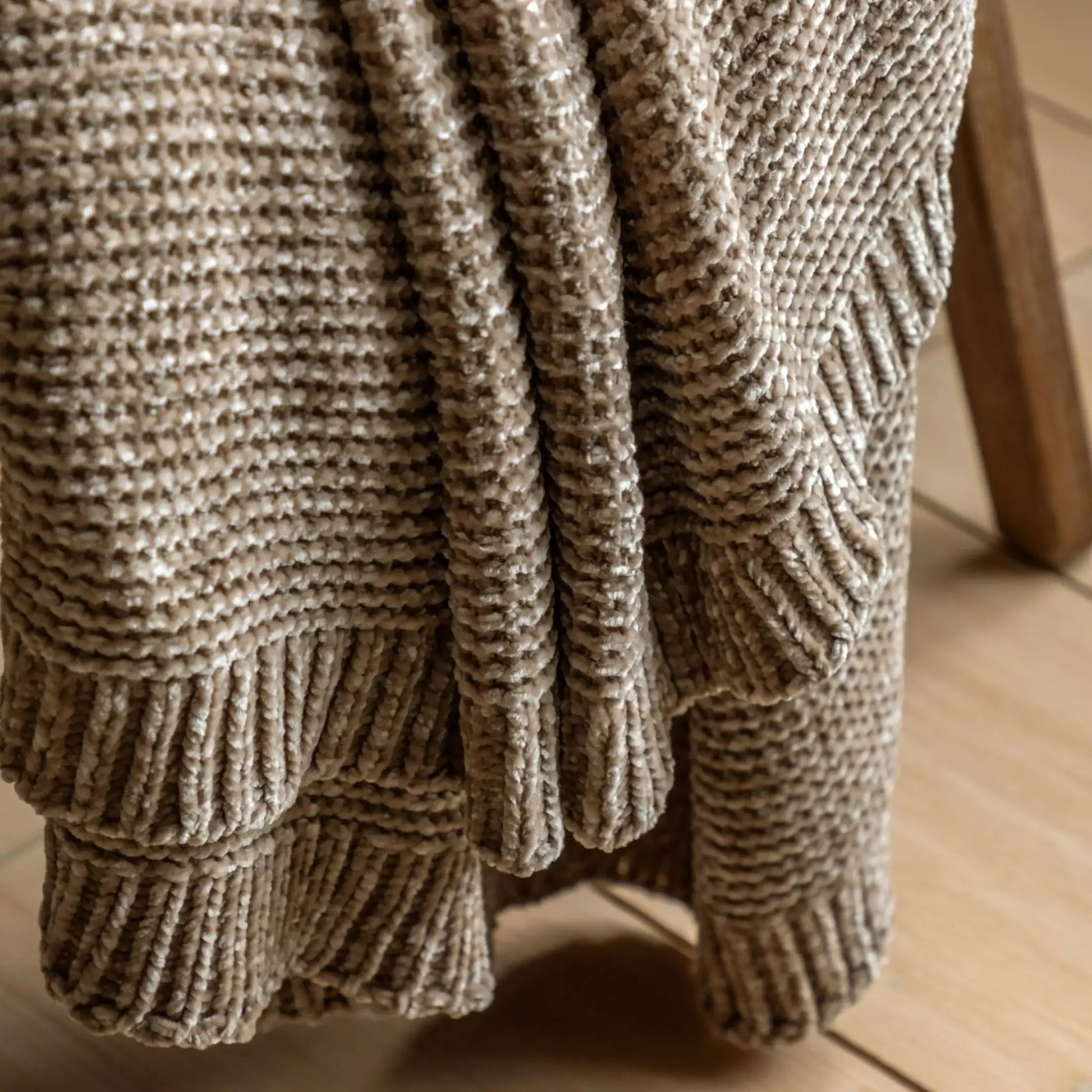 Close-up of a textured brown blanket on a wooden surface