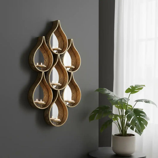 Decorative wall art with teardrop-shaped candle holders on a gray wall with a plant in the foreground.