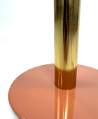 Gold cylindrical object on a pink circular base against a white background