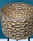 Gold textured planter on a stand against a blue background