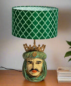 Decorative lamp with a green patterned shade on a wooden surface.