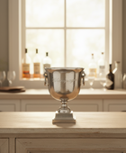 Silver trophy on a wooden surface with a blurred background of bottles and glasses.