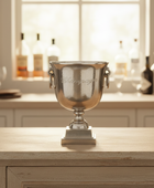 Silver champagne cooler on a wooden surface with a blurred background