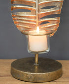Decorative candle holder with leaf design on a wooden surface