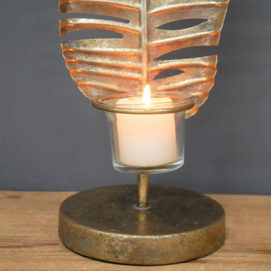 Decorative candle holder with leaf design on a wooden surface