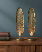 Two leaf-shaped candle holders on a wooden surface with a dark blue wall background