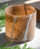Glass candle holder with wooden finish on a surface with greenery