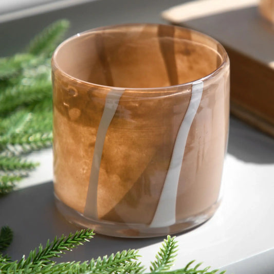 Glass candle holder with wooden finish on a surface with greenery