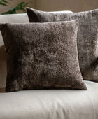Two textured brown pillows on a light-colored sofa with a neutral background