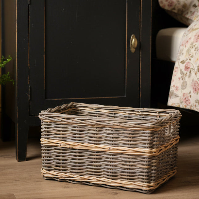 Wicker storage basket on a wooden floor next to a black cabinet.