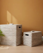 Two woven laundry baskets with lids on a white background