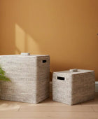 Two woven storage baskets on a wooden floor against an orange wall.