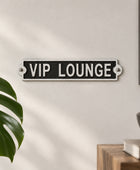 A rectangular black and white metal sign reading 'VIP LOUNGE' mounted on a beige paneled wall.