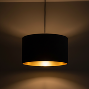 Black pendant lamp with a gold interior on a dark background