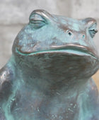 Bronze frog sculpture with a blurred background
