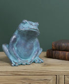 Blue frog statue on a wooden surface with a green wall background