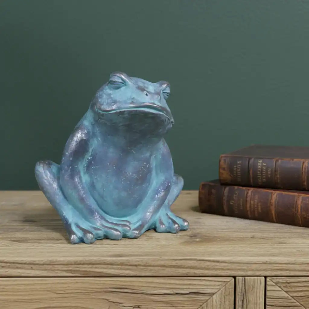Blue frog statue on a wooden surface with a green wall background