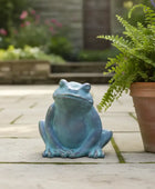 Blue frog statue on a patio with potted plants in the background