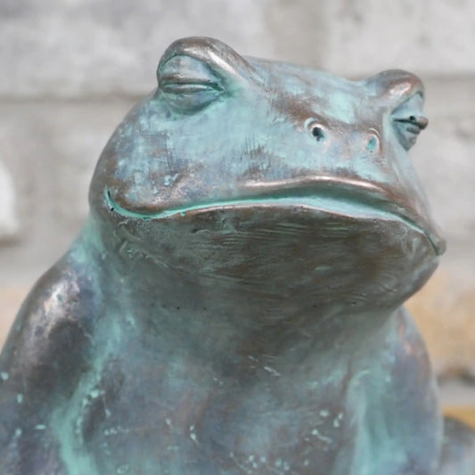 Bronze frog sculpture with a blurred background