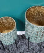 Two decorative pots with gold and teal patterns on a textured surface.