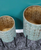 Two decorative pots with gold and teal patterns on a textured surface.