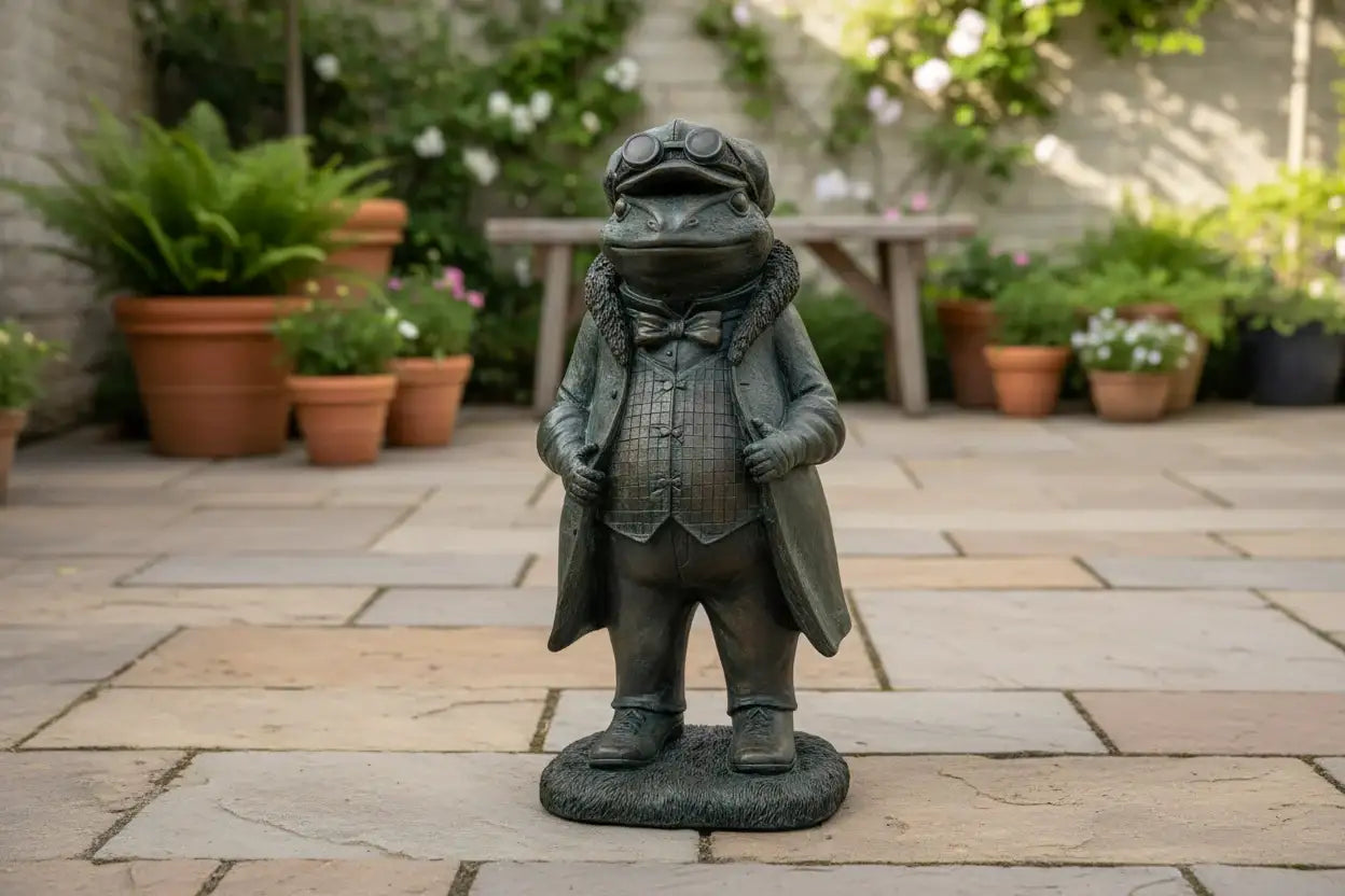 Garden statue of a frog in a suit on a stone patio with potted plants in the background