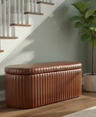 Brown leather ottoman in a room with a staircase and a potted plant.