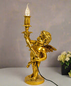 Gold cherub lamp with a light bulb on a gray surface with a neutral background