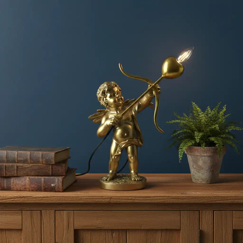 Gold cherub lamp with a light bulb on a wooden surface against a dark blue wall.