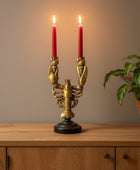 Gold lobster-shaped candle holder with two red candles against a stone wall.