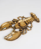 A lobster-shaped metallic brooch in a polished gold finish, displayed on a clean white background.