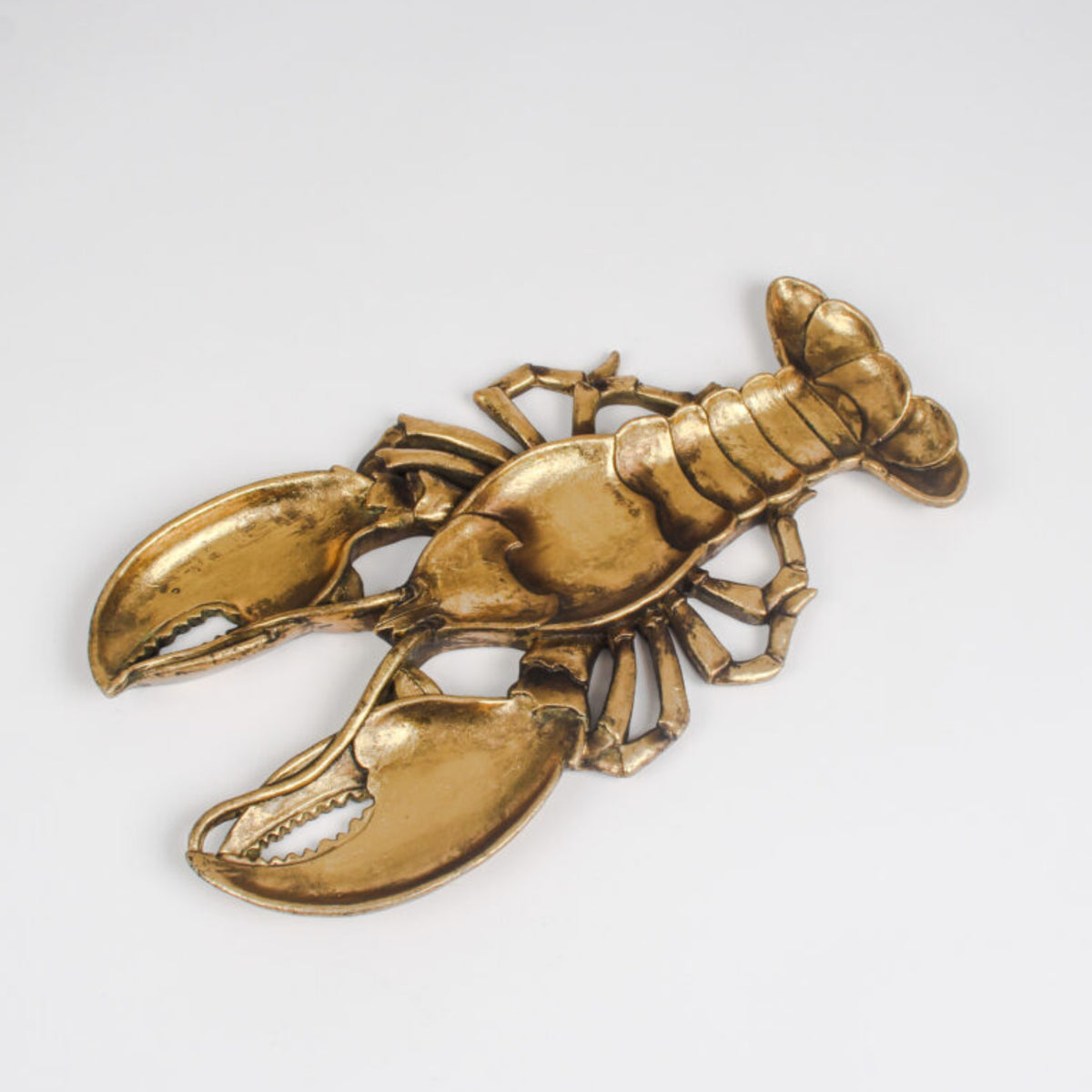 A lobster-shaped metallic brooch in a polished gold finish, displayed on a clean white background.