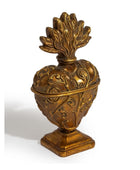 An ornate antique-style gold-toned metal heart-shaped container or decorative sculpture with embossed floral scrollwork and a leaf-like lid, shown on a plain white background.