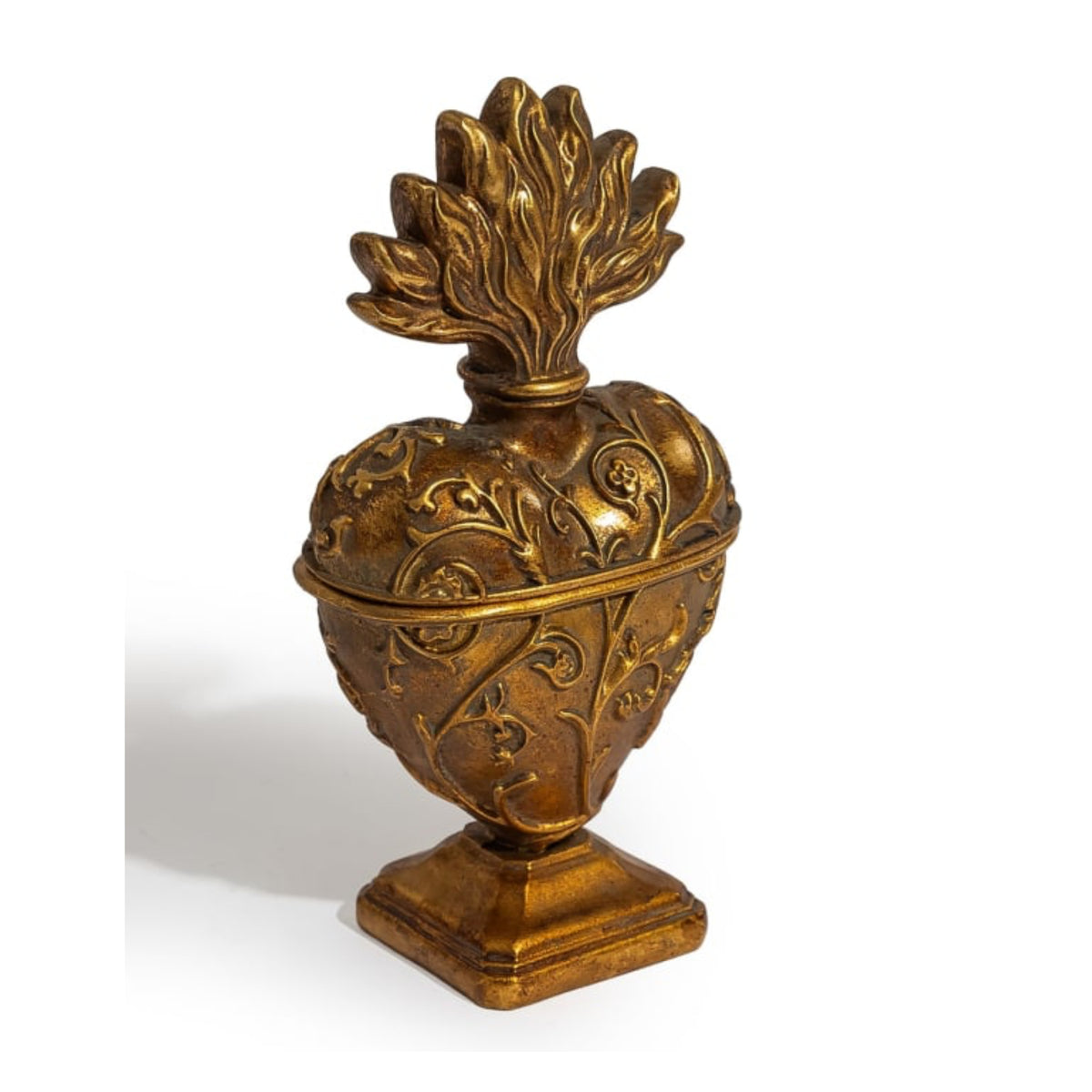 An ornate antique-style gold-toned metal heart-shaped container or decorative sculpture with embossed floral scrollwork and a leaf-like lid, shown on a plain white background.