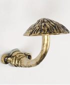 A mushroom-shaped wall hook with a textured metallic finish, featuring a curved stem and a flat cap, shown against a plain white background.