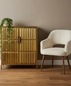 Gold cabinet with textured design next to a white chair on a wooden floor.