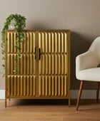 Gold cabinet with textured design in a room with a plant and chair.