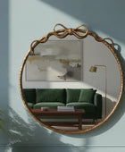 Round gold-framed mirror on a wall with a green sofa and abstract painting in the background.