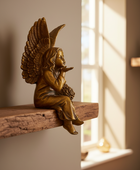 Bronze angel figurine on a wooden shelf with sunlight streaming through a window.
