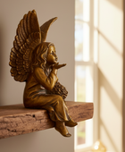 Bronze angel statue sitting on a wooden shelf with sunlight streaming through a window.