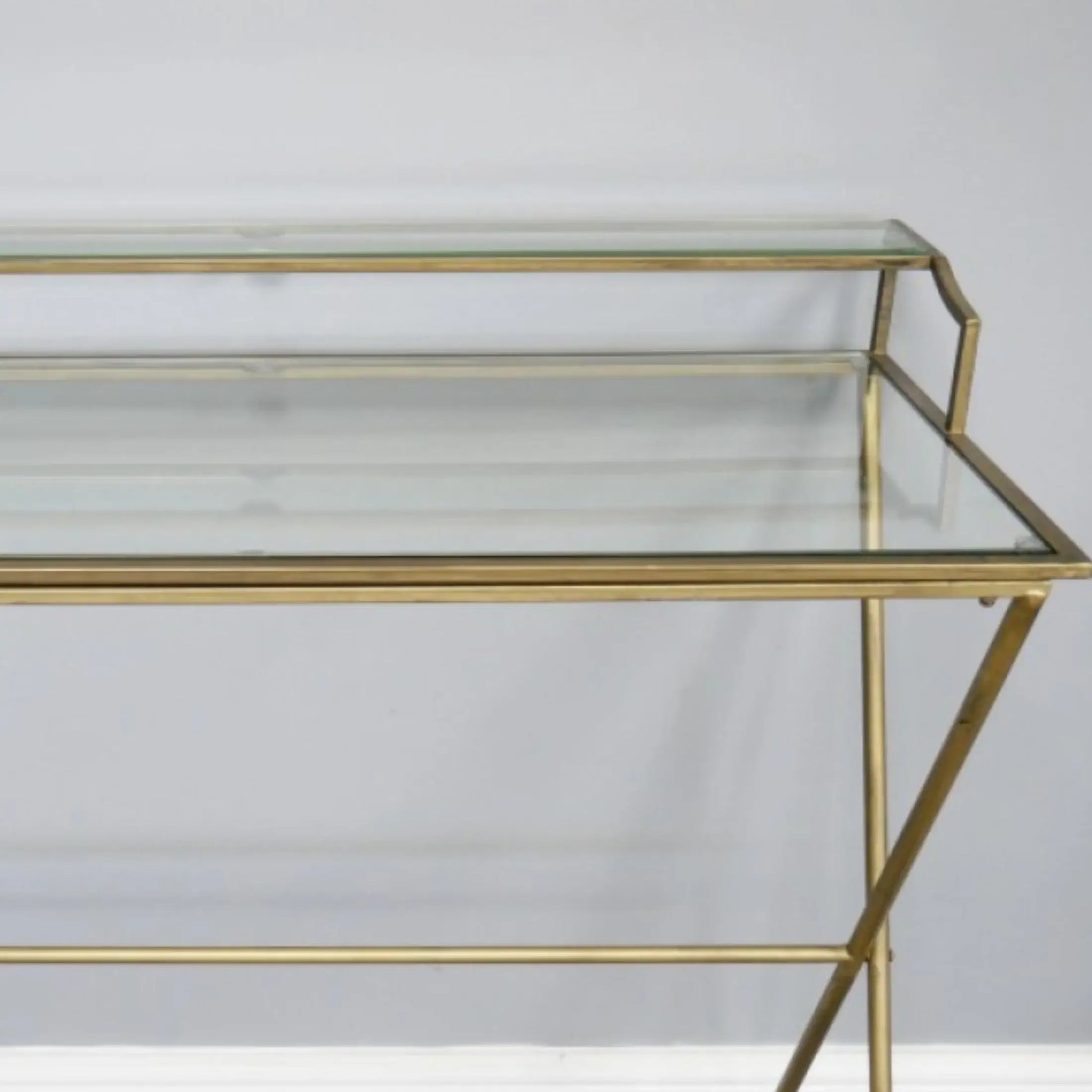Glass console table with gold metal frame on a white background