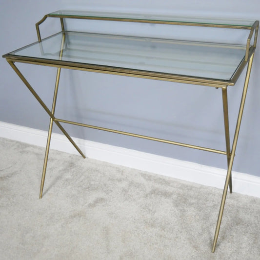 Glass console table with gold metal frame on a neutral background