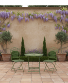 Outdoor patio setting with green chairs and table against a wall with wisteria