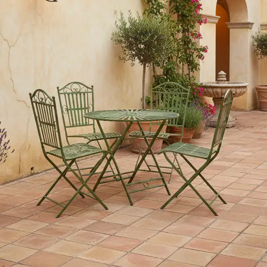 Green metal outdoor furniture set on a tiled patio with decorative plants and architecture.