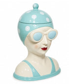 Ceramic jar shaped like a woman's bust with a polka dot lid on a white background