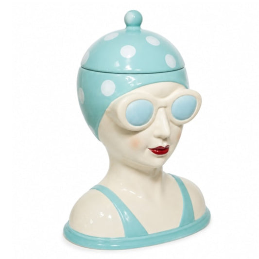 Ceramic jar shaped like a woman's bust with a polka dot lid on a white background