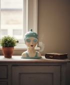 Decorative head with goggles on a wooden surface near a window