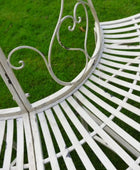 White metal garden bench with decorative backrest on a grassy background
