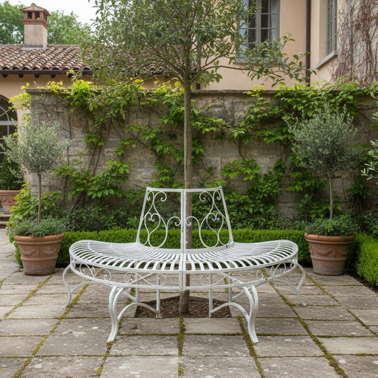White metal garden bench in a stone-walled courtyard with greenery