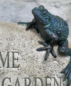 Bronze frog sculpture on a stone with 'Welcome to our garden' engraved.